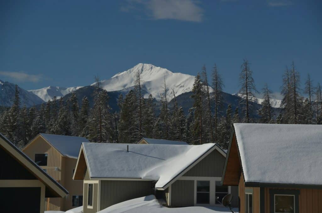 Snow-covered mountain homes in Colorado with a snowy peak behind them