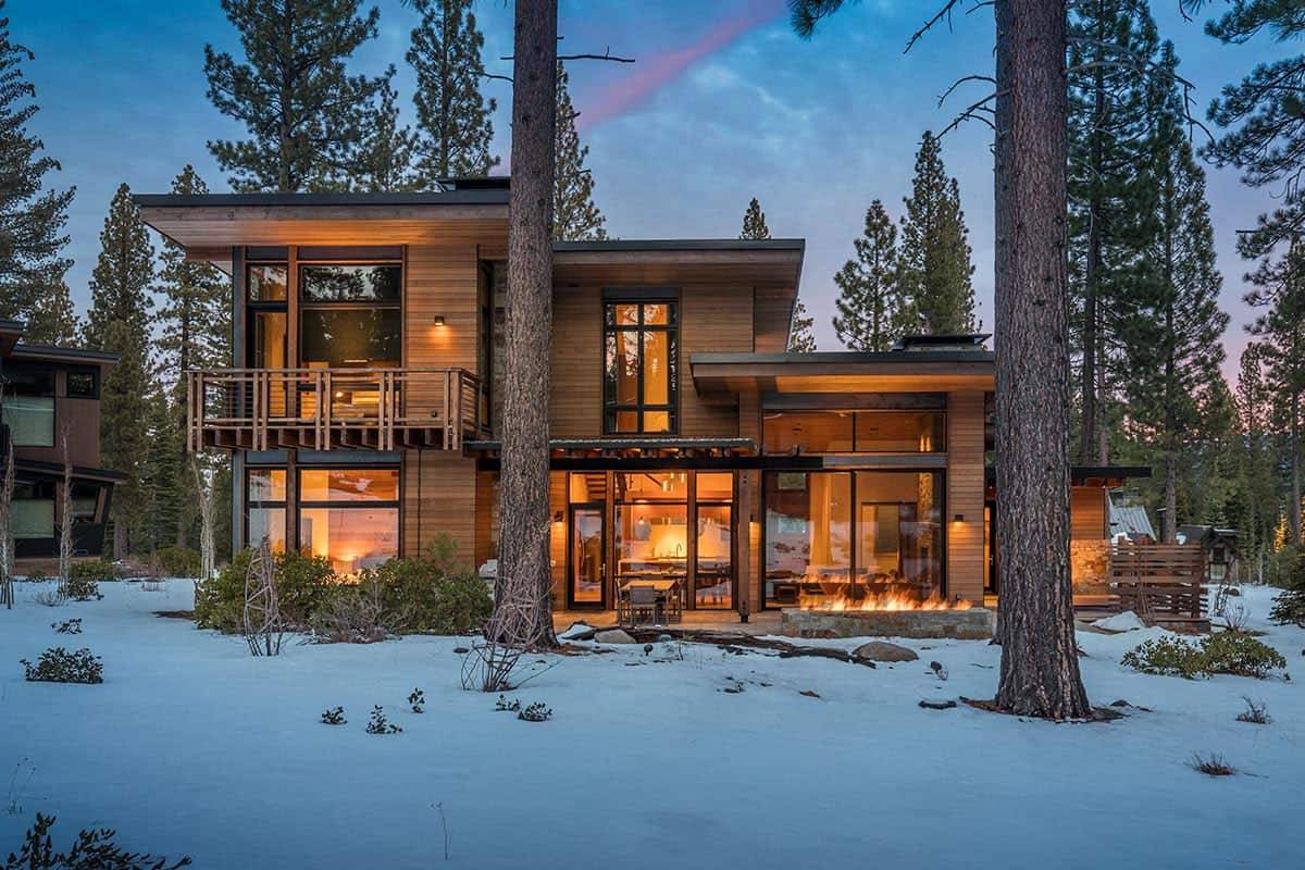 Mountain modern home at dusk in a snowy pine forest